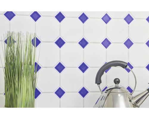 Dekorativa väggplattor med blått rutmönster, vattenkokare i rostfritt stål och konstgjord växt