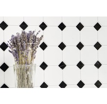 Dekorativ kakelvägg med geometriskt mönster och en bukett lavendel i ett glas.