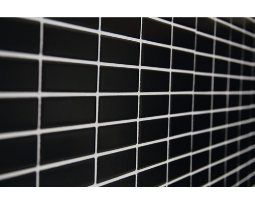 Vägg av svarta, rektangulära plattor med ljus fogmassa