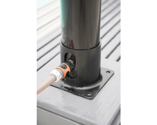 Vattenanslutning till en parasollfot ansluten med en trädgårdsslang.