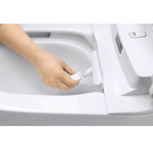 En person byter munstycke på en duschtoalett.