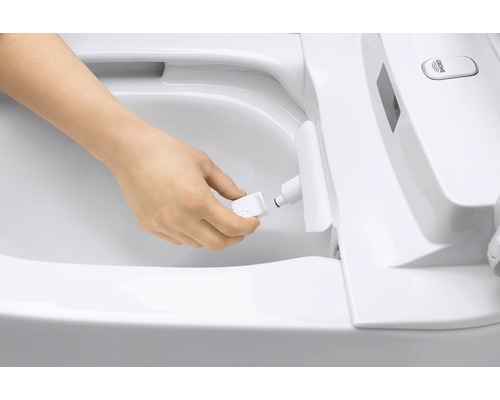 En person byter munstycke på en duschtoalett.