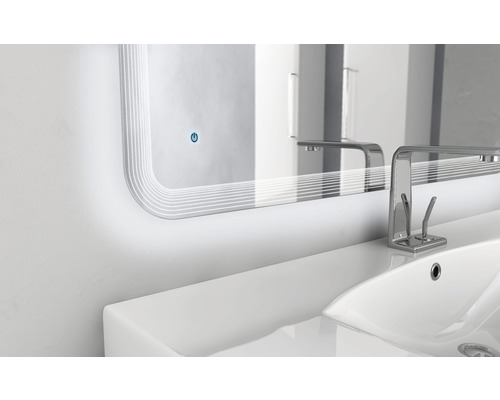 Belyst spegel ovanför ett handfat med kran