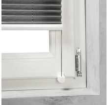 Detaljvy av ett fönster med en grå plisségardin och manöverelement