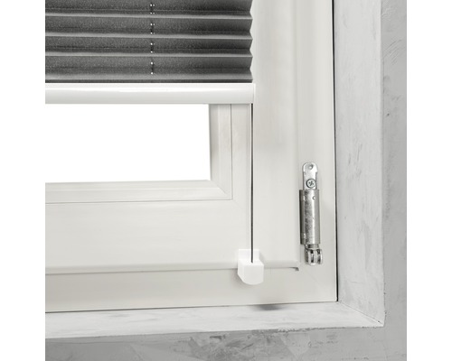 Detaljvy av ett fönster med en grå plisségardin och manöverelement