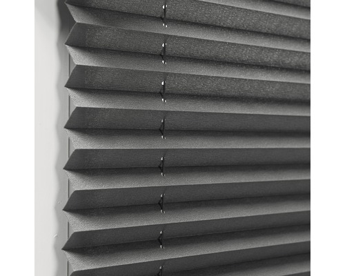 Närbild av en grå plisségardin för fönsterdekoration och solskydd.