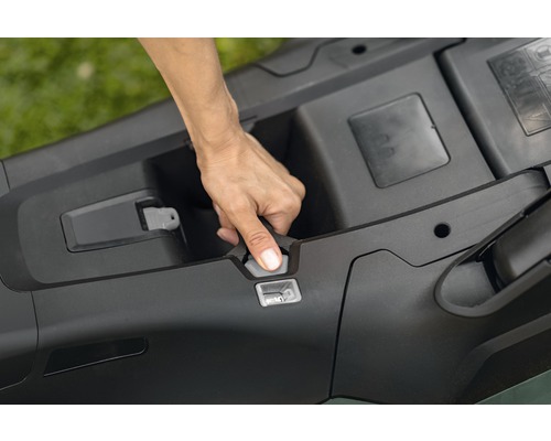 Hand som öppnar batterifacket på en gräsklippare