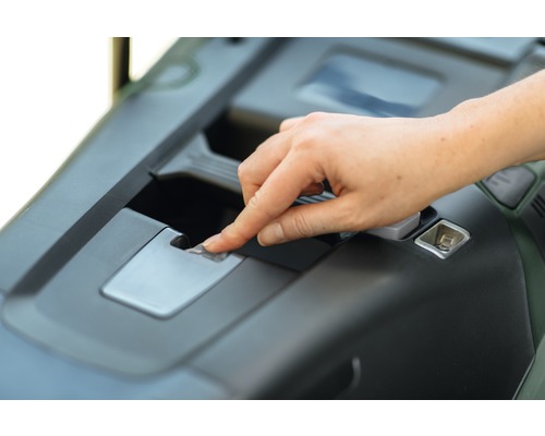 Hand som manövrerar upplåsning på en trädgårdstraktor.