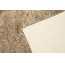Detaljvy av en beige ryamatta med textilbaksida