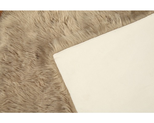 Detaljvy av en beige ryamatta med textilbaksida
