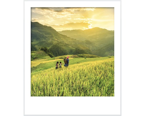 Inramad bild av en lantlig scen med människor på ett fält framför ett kuperat landskap