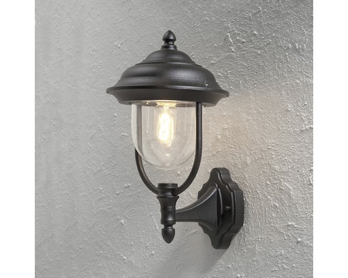 Svart utomhusvägglampa med klart glas och dekorativ design.