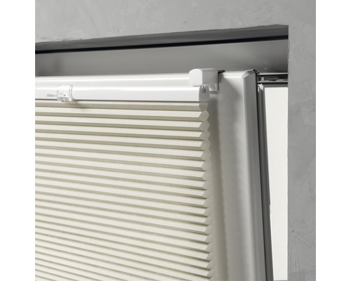 Närbild av en beige plisségardin vid fönstret