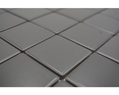 Detaljbild av fyrkantiga, grå keramiska plattor.