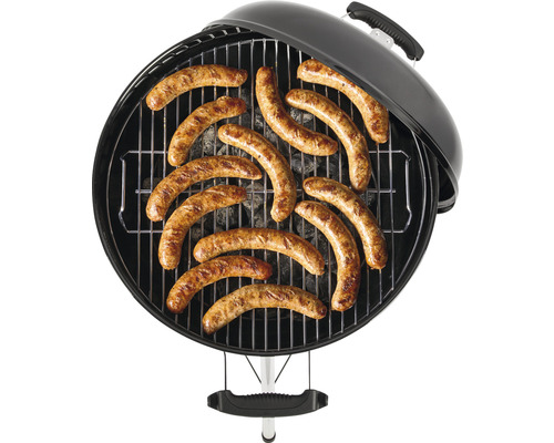 Rund grill med galler och grillade korvar på.