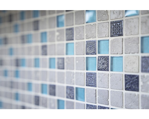 Närbild av en vägg med kvadratiska mosaikplattor i stenlook, glas och med ornament