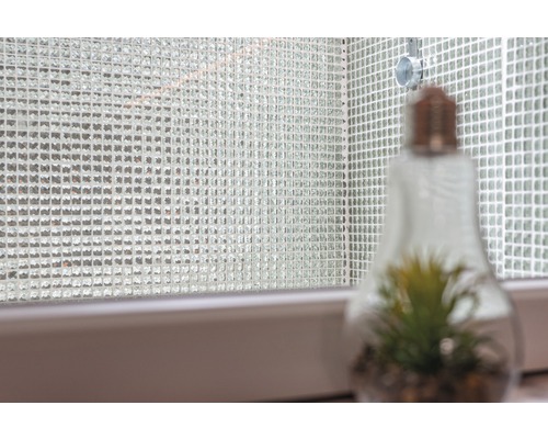 Vägg av mosaikplattor med dekorativ glödlampa med växt