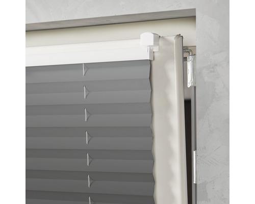 Detaljvy av en grå plisségardin vid fönstret.