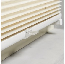 Närbild av en beige plisségardin med vitt fäste för fönsterdekoration.