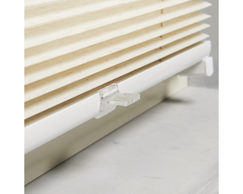 Närbild av en beige plisségardin med vitt fäste för fönsterdekoration.