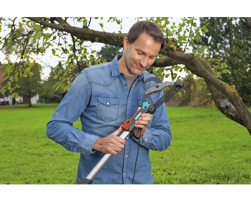 En man använder en grensax i trädgården.
