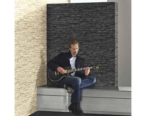 Man spelar gitarr framför en vägg med tapet i stenimitation