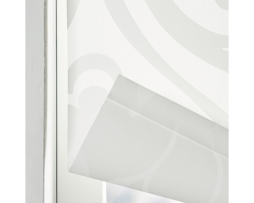 Närbild av en vit rullgardin med mönster i en fönsterram