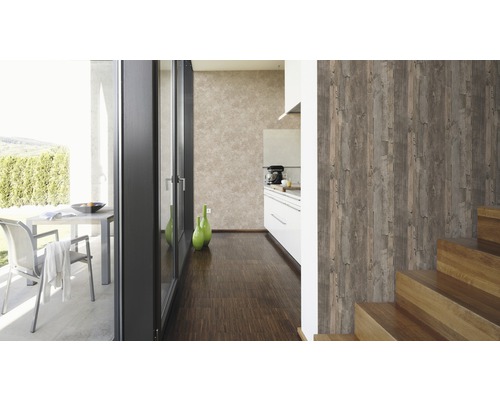 Ljust, organiserat interiör med trägolv, trappa och en väggtapet i träutseende.