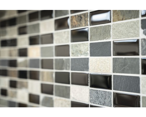 Vägg av mosaikplattor med rektangulära plattor i olika gråtoner och texturer