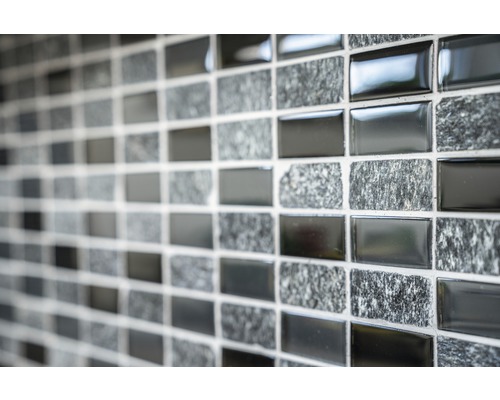 Närbild av en mosaikvägg med omväxlande glänsande och stenliknande ytor