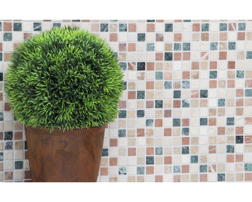 Konstgjord växt i kruka mot en mosaikbakgrund