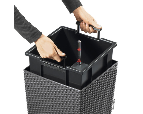 Person som sätter in en växtinsats med vattennivåindikator i en blomlåda.