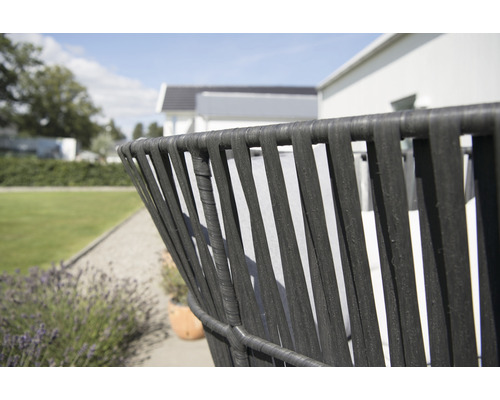 Detaljvy av en svart rottingfåtölj i en trädgård