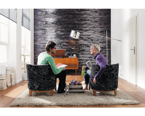 Vardagsrum med två personer i fåtöljer, golvlampa och dekoration på en matta