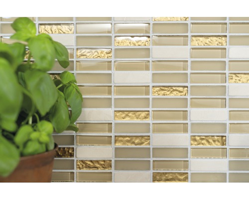 Vägg med mosaikplattor med glas- och guldaccenter samt en basilikaväxt i en kruka