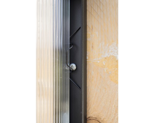 Detaljvy av en transparent kanalplastskiva, fixerad med en skruv och en fästklämma på en ram