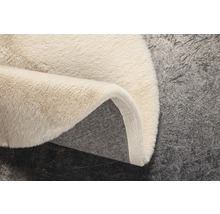 Detaljvy av en beige ryamatta med textilbaksida