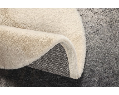 Detaljvy av en beige ryamatta med textilbaksida