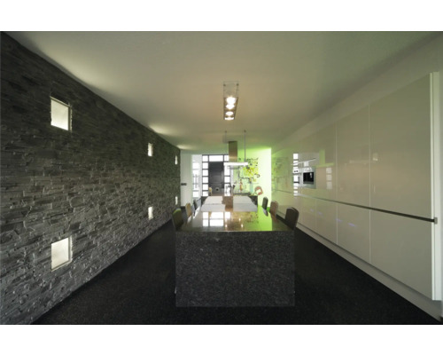 Ljust rum med stendekorativ vägg, matbord och pentry.