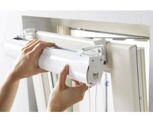 Person monterar rullgardin på fönsterkarmen