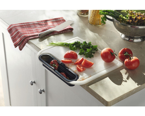 Köksscen med skärbräda, grönsaker och avfallsbehållare.