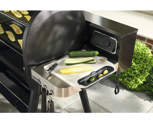 Grillscen med zucchini på skärbräda bredvid grill