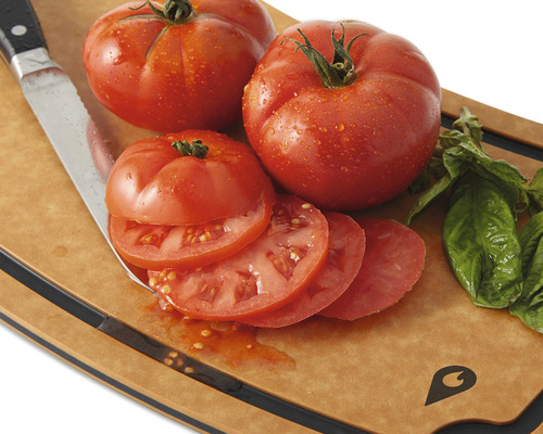 Tomater, basilika och kniv på en skärbräda