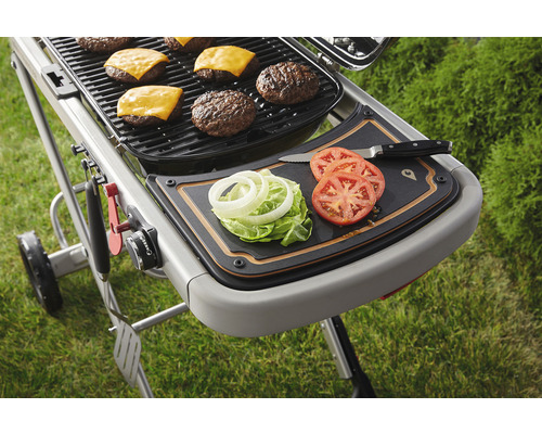 Grill med hamburgare, ost, tomater, sallad och lök på en skärbräda