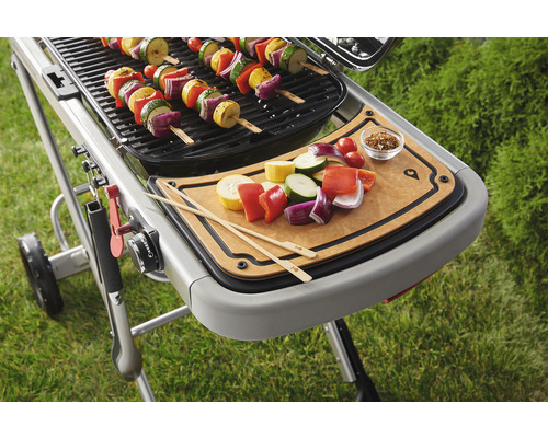 Grill med grönsaksspett och skärbräda för att förbereda fler spett