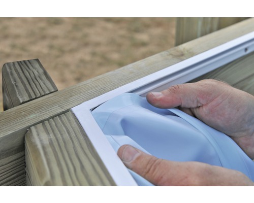 Person monterar en vit insynsskyddsfilm i en träram.