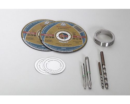 Två kapskivor, en metallring, två gängtappar, borrar och runda klistermärken ligger på ett bord.