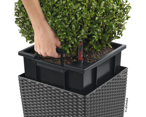 Närbild av en blomkruka med bevattningssystem och vattennivåindikator med en hand på insatshandtaget