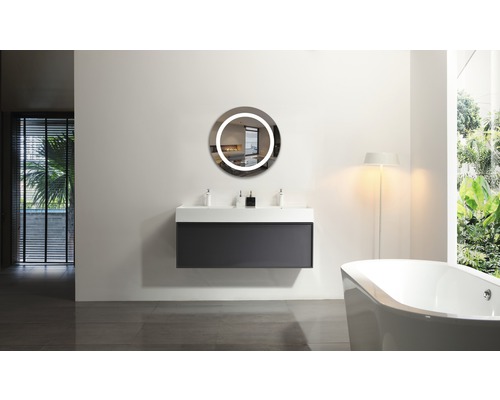 Modernt badrum med tvättställ, rund spegel med belysning och badkar