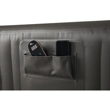 Detalj av en uppblåsbar bubbelpool med två fickor, som innehåller en fjärrkontroll och en smartphone.